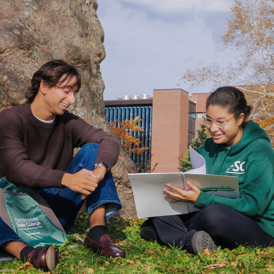 Students seated by a tree near Gleeson Plaza